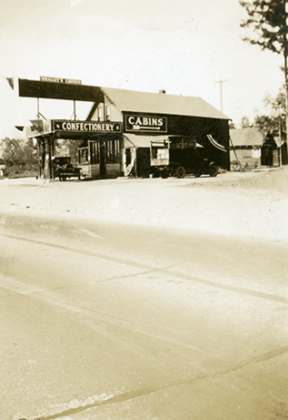 View of Service Station from Pacific Highway. Automobile at pump. Cabin & Confectionary sign visible